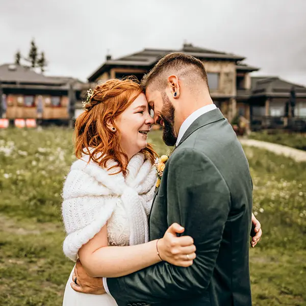 Ein Brautpaar vor der Berghütte zur Hochzeit am Katschberg auf einer blühenden Sommerwiese in den Bergen.
