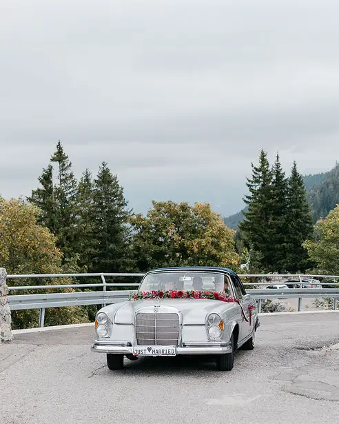 Als Brautauto ein in Beerentönen dekorierter silberner Oldtimer inkl. Chauffeur.
