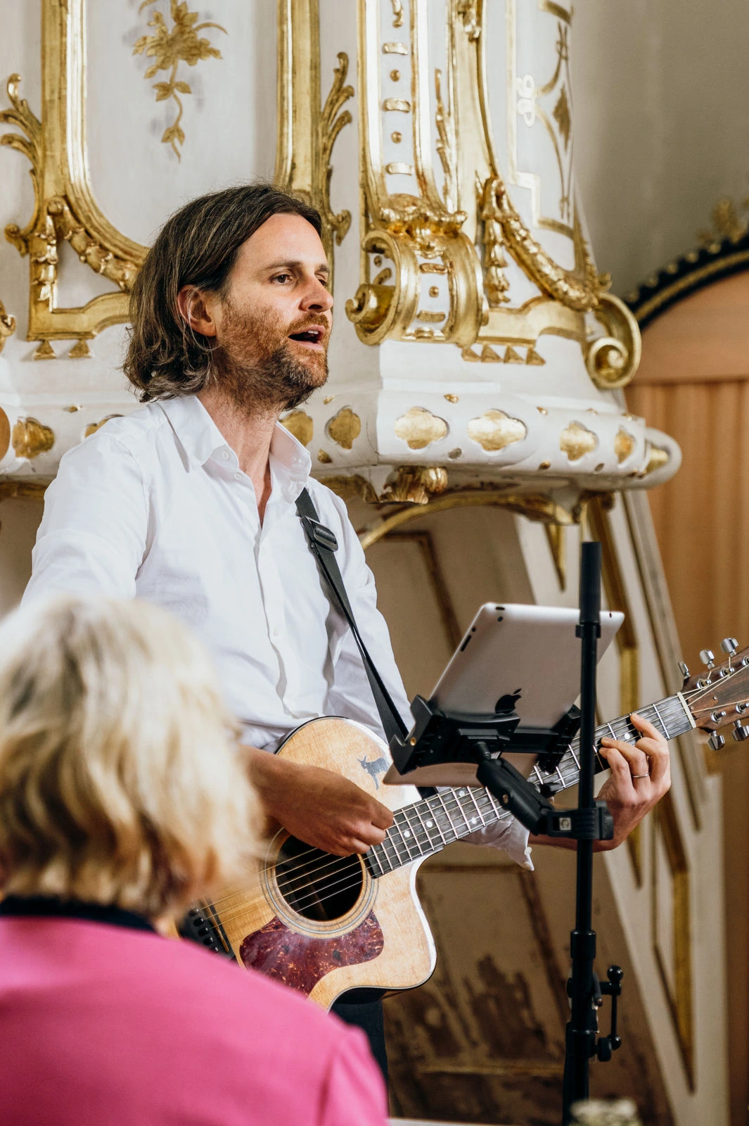 Hier ist ein Sänger zu sehen mit Gitarre in einer kleinen Kapelle bei einer intimen Hochzeit.
