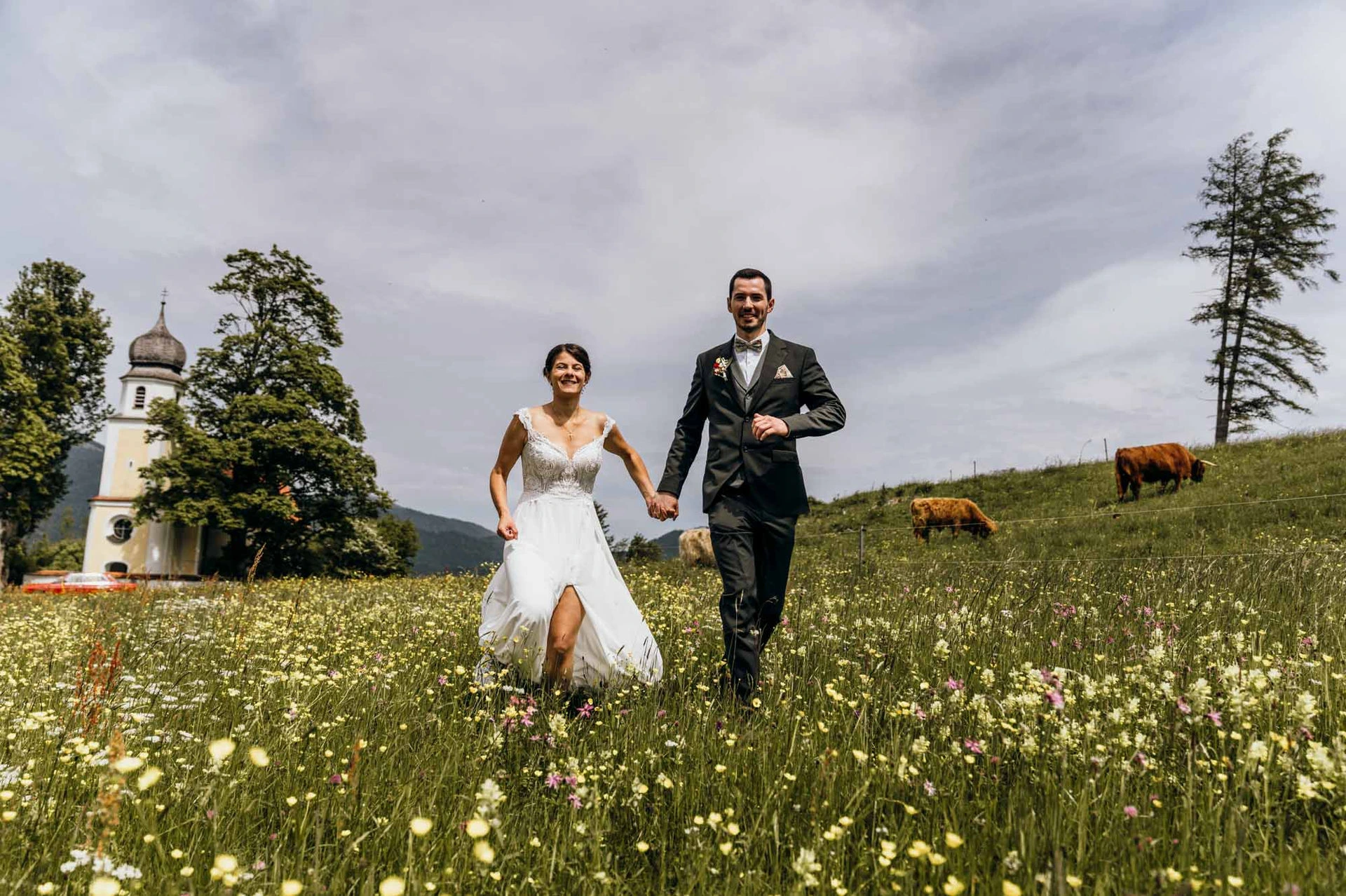 Ein Brautpaar mit kleiner Gästeliste bei ihrer Sommerhochzeit auf einer blühende Wiese zu zweit